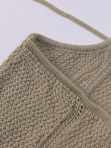 Detail of hollow knit texture and delicate tie straps on a beige crochet maxi dress