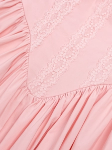 Detail of pink dress featuring delicate floral lace trim and pleated fabric textures