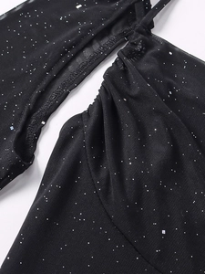 Détail macro de la robe en maille noire avec paillettes argentées et fronces élégantes