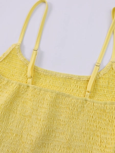 Detail of yellow smocked dress featuring adjustable spaghetti straps and elastic texture
