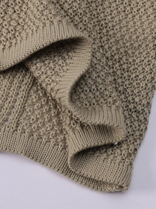 Close-up of khaki crochet knit fabric detail with intricate mesh hollow-out pattern