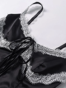 Nahaufnahme eines schwarzen Satin-Camisoles mit weißer Spitze und Schleifendetails