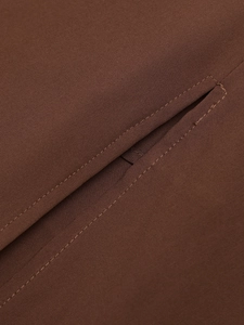 Close-up of a brown dress showing the detailed stitching on the fishtail slip pocket