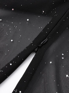 Dettaglio macro della cerniera invisibile su abito in rete nera con paillettes d'argento