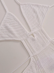 Detailed view of white crochet knit texture and hollow-out floral patterns on the dress