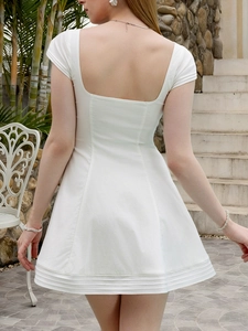 Detailed back view of white square neck backless dress with elegant pleated hem and sleeves