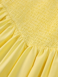 Close-up detail of the yellow shirring and pleated fabric on the mini A-line dress