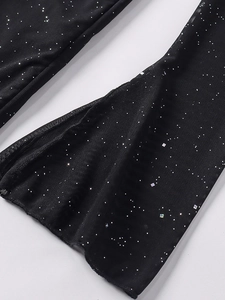Détails du tissu en maille noire avec strass brillants sur le bas de jambe évasé