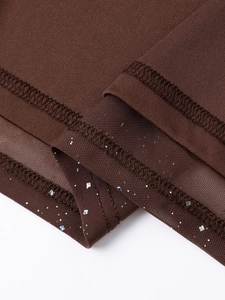 Détail du tissu en maille marron avec paillettes argentées et coutures sur la robe