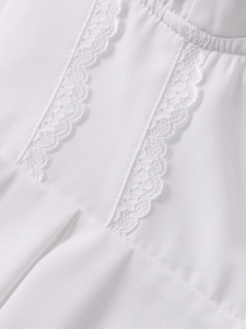 Dettaglio del delicato pizzo floreale bianco e del tessuto a pieghe sull'abito
