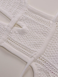 Detail of white crochet knit dress showing intricate hollow out patterns and texture
