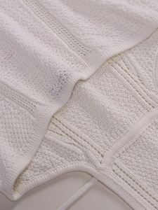 Detailed macro shot of white hollow-out knit fabric texture with tie strings