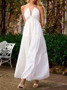 Detail of white tiered maxi dress with deep V-neck and halter straps for beach vacation
