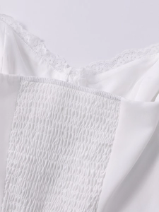 Dettaglio dell'abito bianco con bordo in pizzo e dettaglio smock elastico sulla schiena