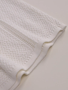 Detailed macro view of white knitted hollow-out lace fabric with ribbed cuff textures
