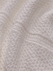 Close-up of white crochet knit texture with thick embossed woven patterns and soft fabric