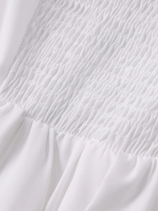 Dettaglio della lavorazione smocking sull'abito bianco a trapezio con trama plissettata
