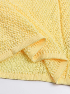 Detailed macro shot of yellow knit dress featuring hollow diamond pattern and ribbed hem