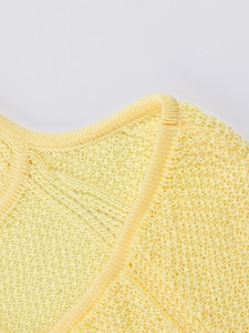 Detailed close-up of light yellow knit halter dress neckline with neat stitching