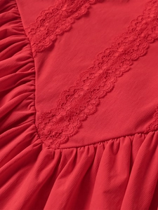 Detail of red dress showing elegant lace stitching and fine pleated fabric texture