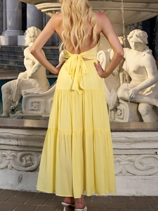 Detailed back view of a yellow halter maxi dress with a large bow tie and tiered skirt