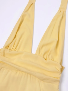 Detail eines hellgelben Neckholder-Kleids mit tiefem V-Ausschnitt und Taillenfalten