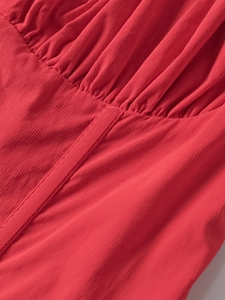 Detail of red fishbone dress showing vertical pleats and textured crepe fabric stitching