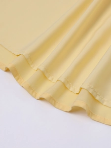 Detail des hellgelben Chiffon-Kleidsaums mit doppellagiger Wellenrüsche und sauberer Naht