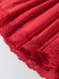 Detailed macro view of the elegant red lace patchwork and pleated hem on the dress