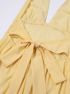 Detail des gelben Neckholderkleides mit offenem Rücken, großer Schleife und Faltenbund