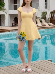 Detail of light yellow mini dress featuring a sweetheart neckline and slim waistline