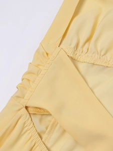 Detailaufnahme des hellgelben Chiffonkleids mit geraffter Taille und feinen Nähten