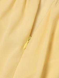 Nahaufnahme des unsichtbaren Reißverschlusses an einem hellgelben Chiffon-Neckholder-Kleid
