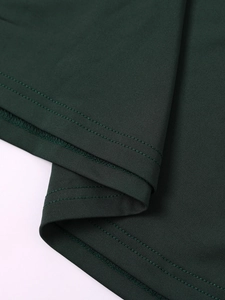 Detail of professional double-needle stitching on the hem of a dark green maxi dress