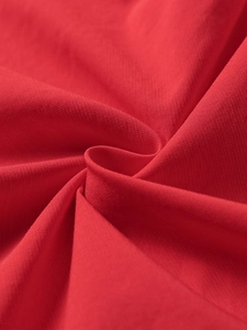 Macro detail of red dress fabric showing fine textile texture and soft draping quality