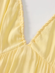 Detailed close-up of pale yellow deep V-neck dress with elegant pleated texture fabric