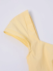 Detail view of layered ruffles and textured fabric on light yellow A-line mini dress