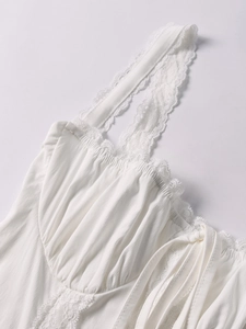 Detail of white dress with lace shoulder straps and gathered bust with a tie
