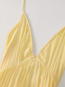 Detailed close-up of light yellow deep V-neckline with delicate pleated fabric textures