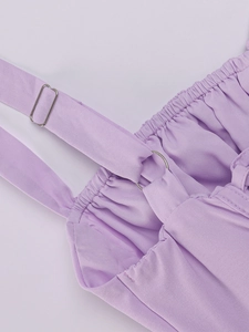Detail view of adjustable silver metal buckles and lavender shirred fabric on the dress