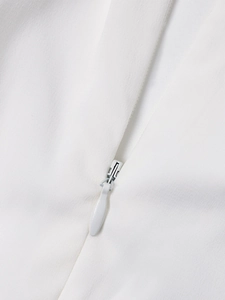 Detailaufnahme eines weißen verdeckten Reißverschlusses an einem eleganten Chiffonkleid