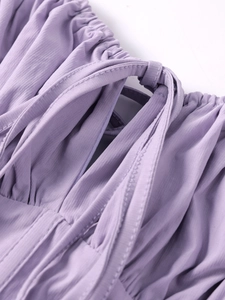 Macro detail of lavender lace-up mini dress featuring textured fabric and ruffle trims
