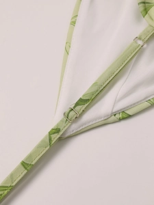 Detailed close-up of adjustable strap on mesh dress with green leaf print and silver buckle