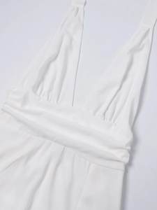 Detail des weißen Neckholder-Kleids mit tiefem V-Ausschnitt und plissiertem Taillendesign