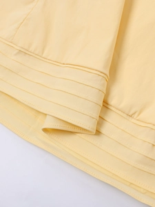 Detail of cream yellow fabric with multi-layered parallel pleats and fine vertical texture