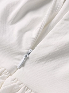 Detailed close-up of invisible zipper on white textured fabric of a cocktail dress