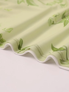 Detail of the ruffle edge hem and green leaf print on soft mesh fabric material