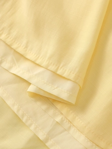 Detail of light yellow maxi dress hem showing smooth lining and fine woven texture