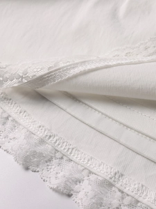 Close-up detail of white lace trim and multi-layer fabric on an elegant A-line dress