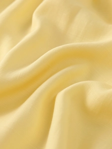 Close-up of pale yellow stretch fabric featuring vertical texture and soft drape detail